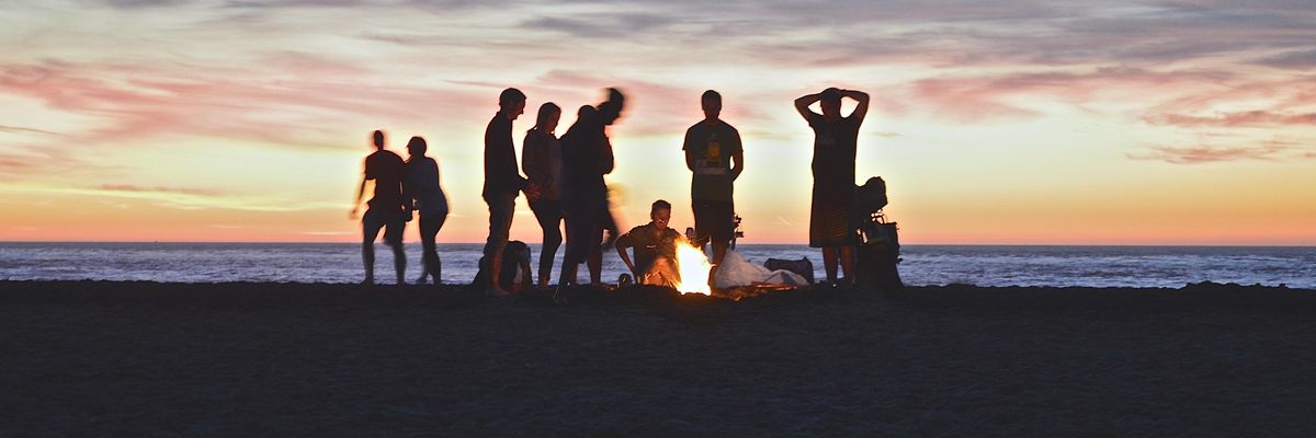 egy baráti társaság a tengerparton a tűz körül