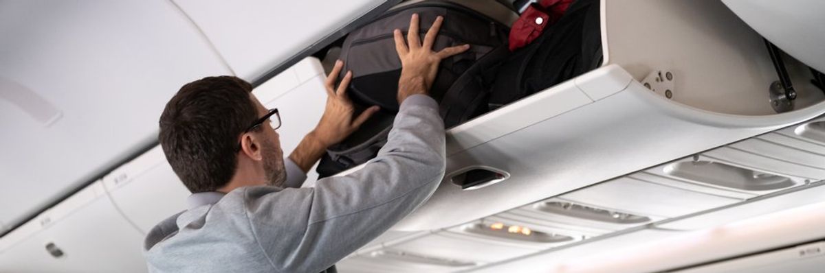 egy férfi felteszi a csomagját a repülőgépen