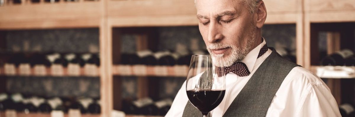 egy férfi szagolja a vörösbort egy pohárban