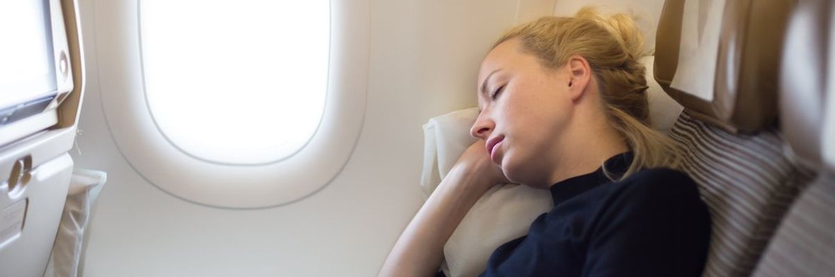 Egy nő alszik a repülőn.