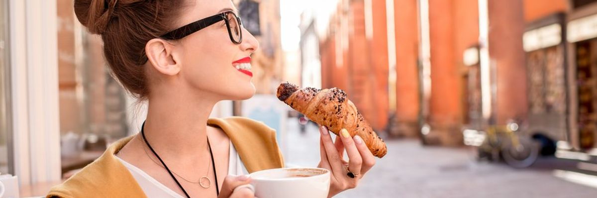 egy nő croissantot eszik és cappuccinot iszik Bolognában