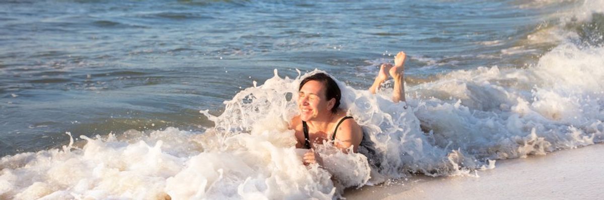 egy nő fürdőzik az óceán szélén