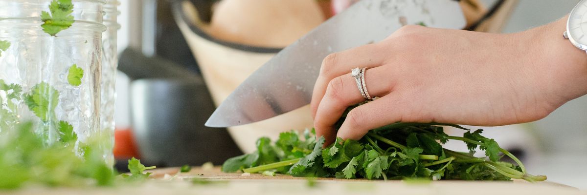 Egy nő kést tart a kezében és zöldséget vág