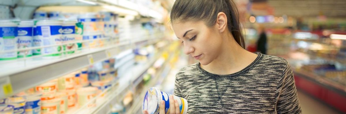 egy nő vizsgálja a joghurtot a boltban a hűtött részlegnél