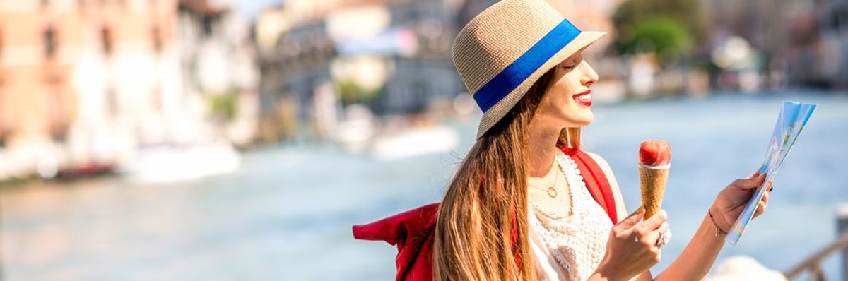 egy turista nő kalapban fagylaltot eszik és térképet nézeget Olaszországban