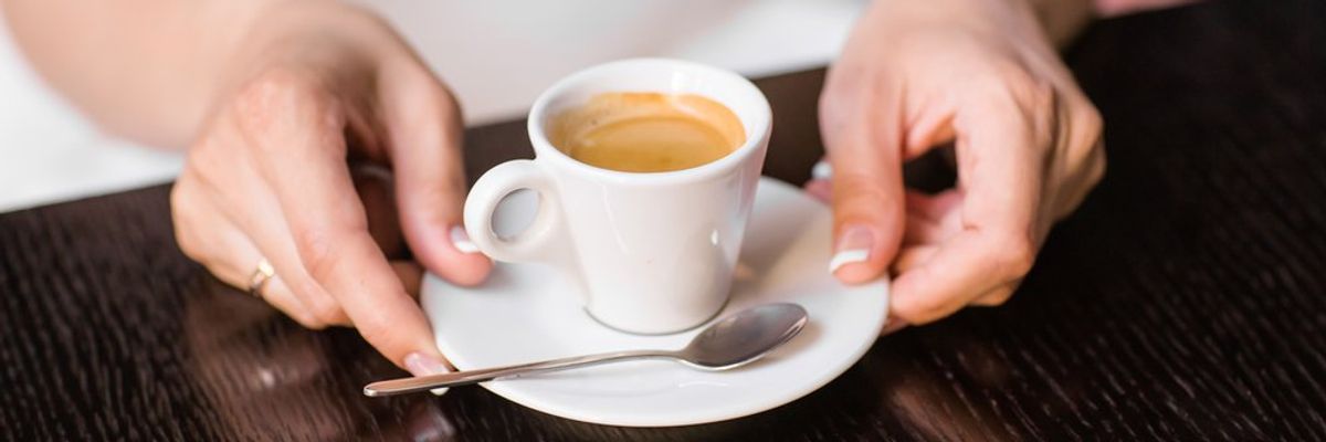 espressot fog a két keze között egy nő egy fehér csészében
