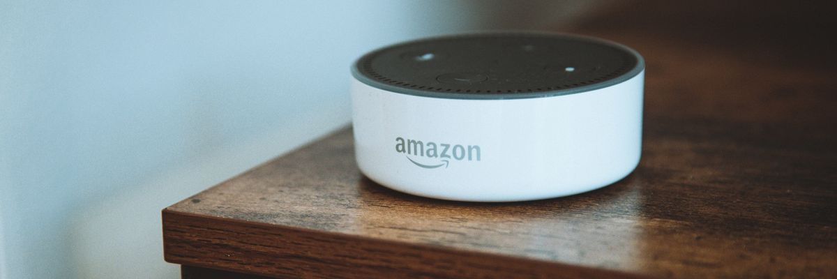 fehér Amazon Alexa egy barna fa borítású asztalon