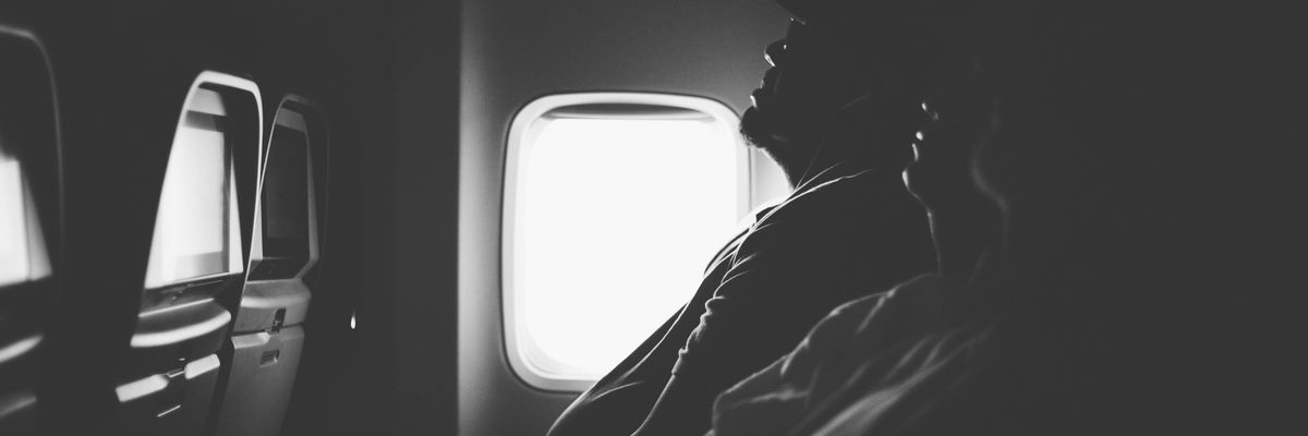 grayscale photo of three person sitting inside airplane