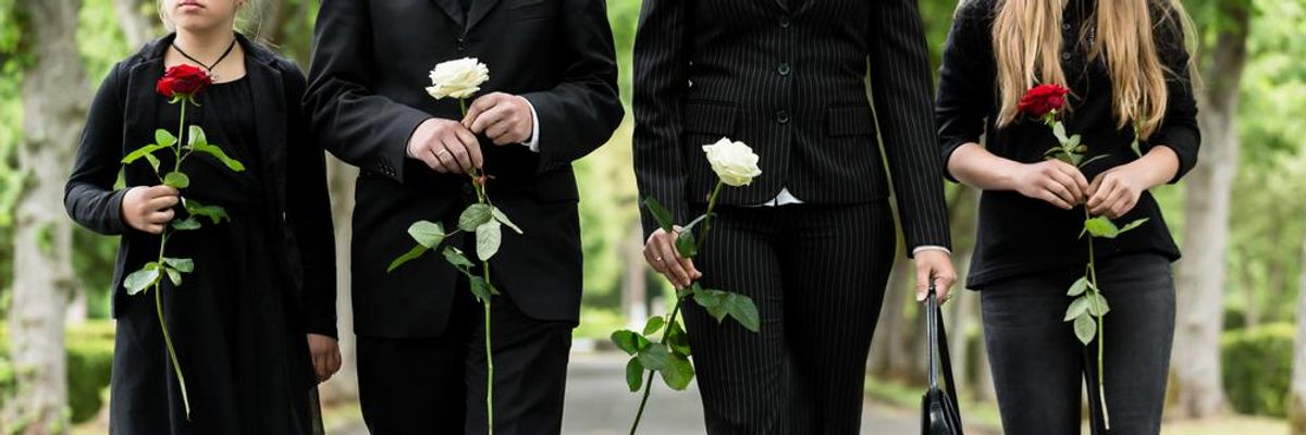gyászoló, feketébe öltözött emberek egy-egy szál rózsával a kezükben