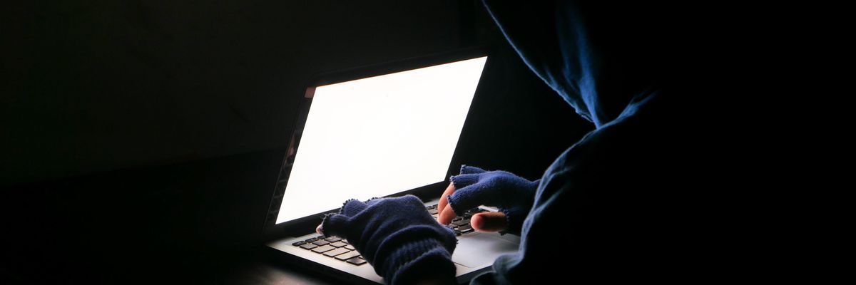 hacker, csaló ül a laptop előtt sötét szobában