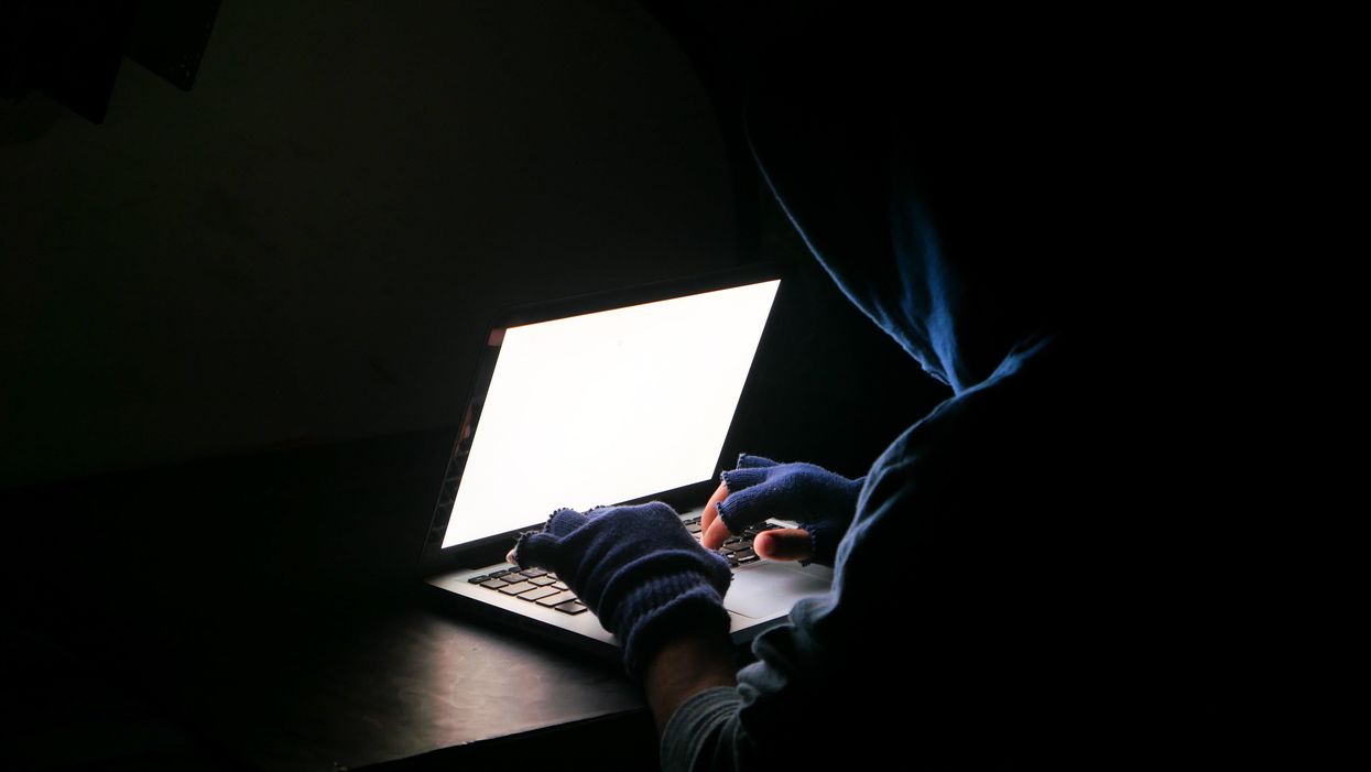 hacker, csaló ül a laptop előtt sötét szobában