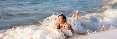 egy nő fürdőzik az óceán szélén