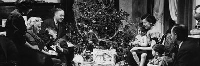 1940-es években egy család ül a karácsonyfa előtt ajándékokkal körülvéve