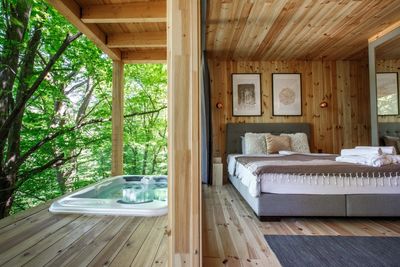 lomb jakuzzi pezsgőfürdő terasz erkély faház franciaágy szőnyeg ágynemű parketta párna kép lámpa fal tükör ágynemű törölköző fa