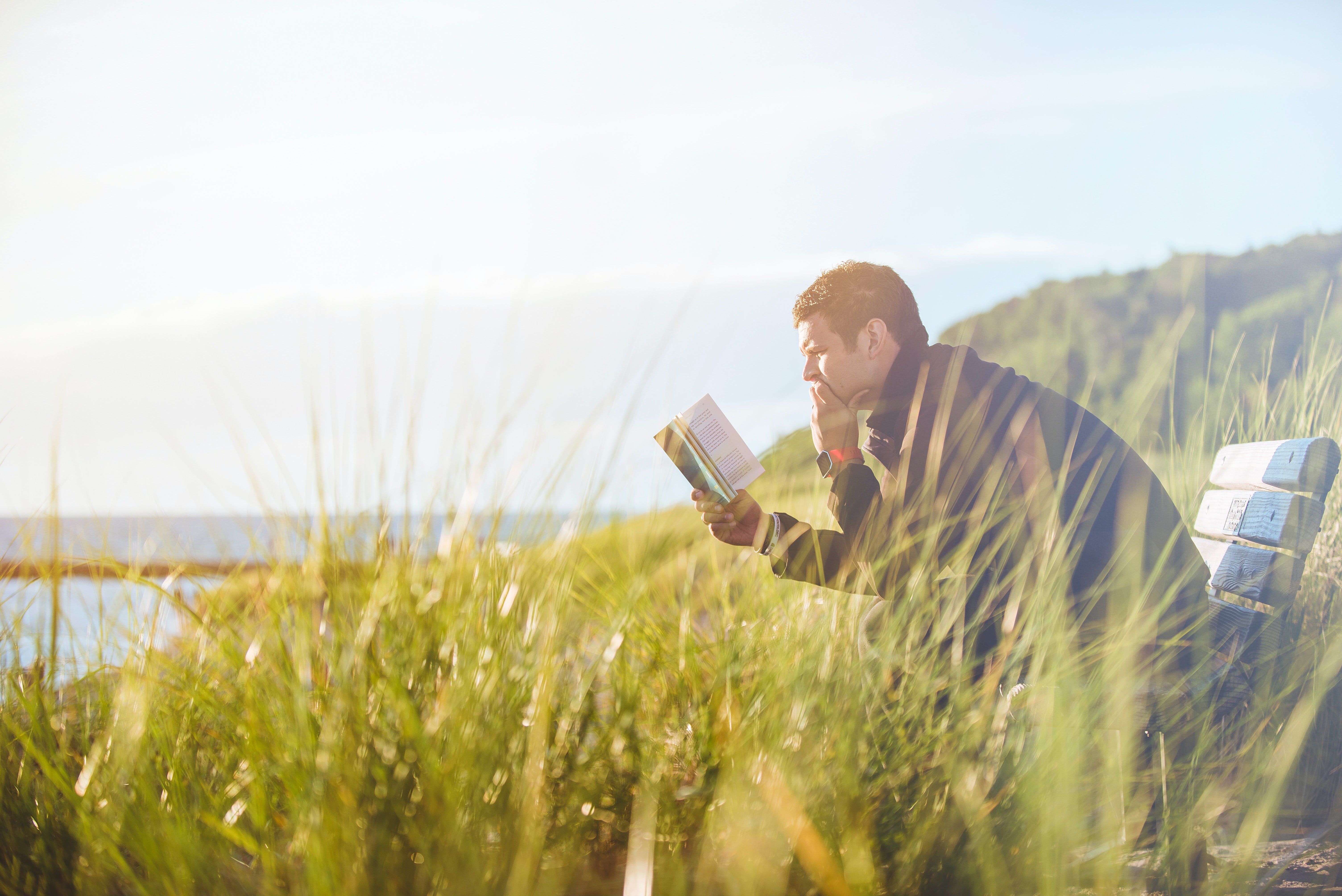Olvasó férfi a tengerparton, könyvvel a kezében