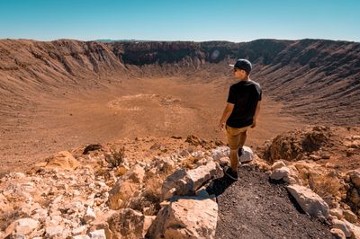 Baseball sapkás férfi áll egy kráter szélén