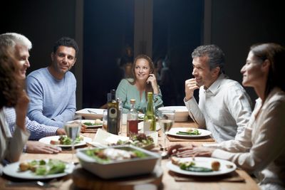 vacsorázó emberek egy nagy étkezőasztal körül tele mindenféle finom gusztusos étellel