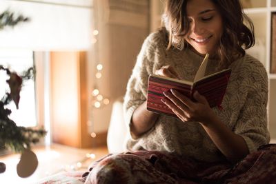 karácsonyfa nő kötött pulóverben naplót ír mosolyog szoba