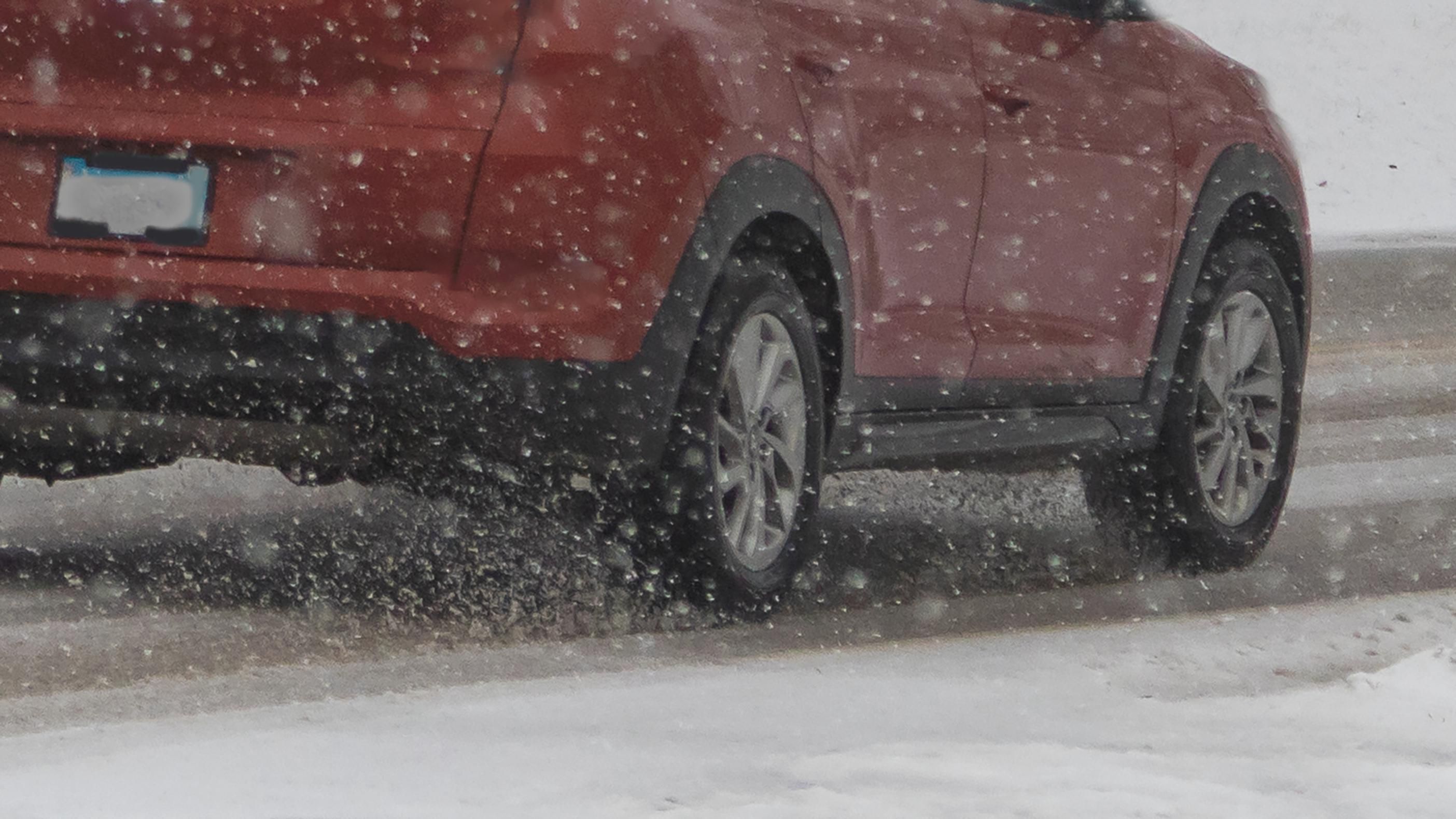 piros autó a csúszós havas országúton télen