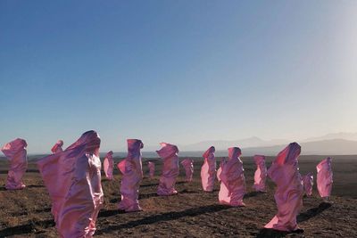 rózsaszín zsákokban állnak emberek egy mezőn