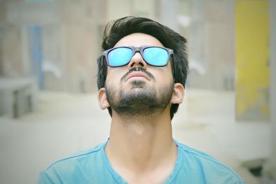 kék póló napszemüveges szakállas férfi az eget bámulja sötét haj