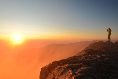 napfelkelte a hegyekben fotós férfi fotóz képet készít egy sziklán állva fényképezőgéppel