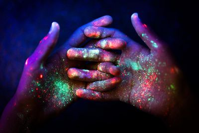 összekulcsolt kezek rajtuk színes fényekkel