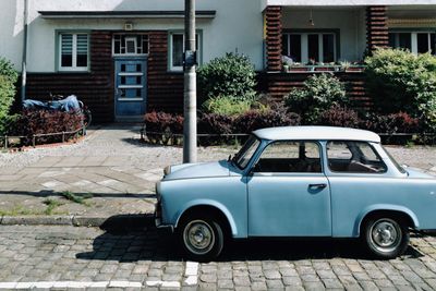 Egy kék színű Trabant egy ház előtt parkol