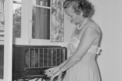 légkondi, légkondicionáló, hölgy beállítja a légkondit az ablaknál állva