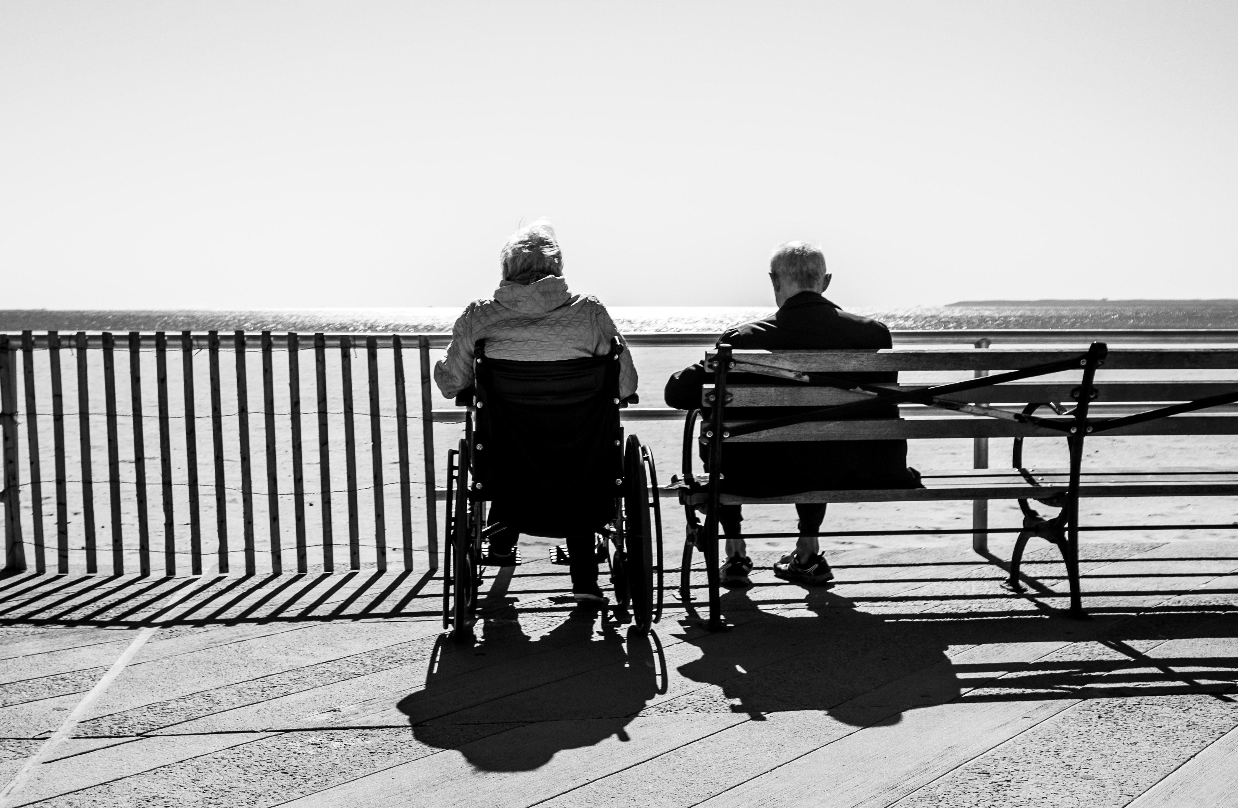 Két idős ember, háttal a kamerának ülnek egy hídon
