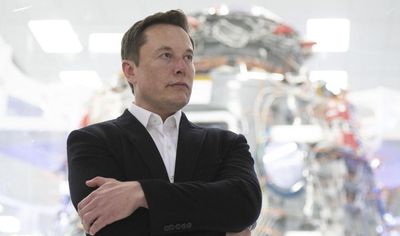 Elon Musk egy fekete öltönyben áll.
