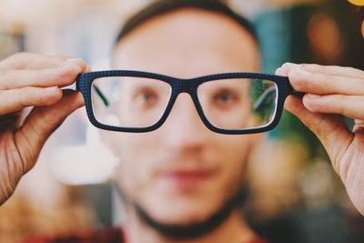 person holding eyeglasses with black frames