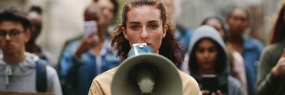 Fiatal lány egy hangosbemondóval tüntet 