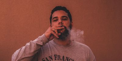 man wearing gray San Francisco long-sleeved shirt while smoking
