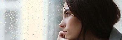 szomorú nő néz ki az esős ablakon