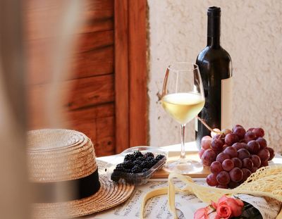 asztal borral szőlővel kalappal és egy csokor rózsával 