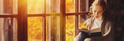lány olvas az őszi ablakban