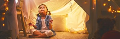 kislány meditál egy játék sátor alatt a szobában