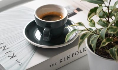 kávé csészében egy könyv tetején virág mellett 