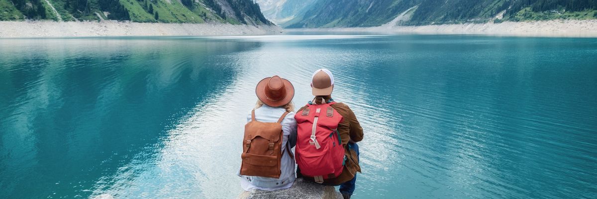 két turista ül egy sziklán egy tó előtt