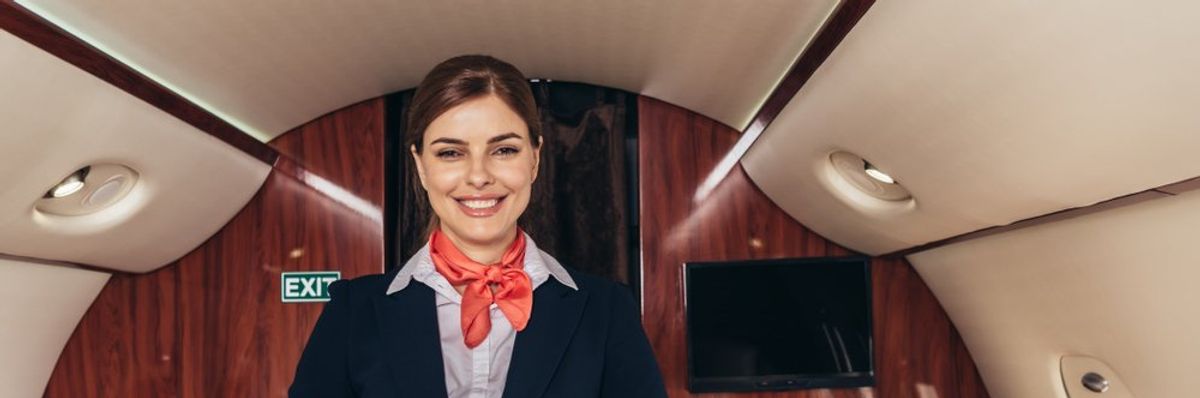 légiutas-kísérő hölgy a repülőn mosolyog a kamerába