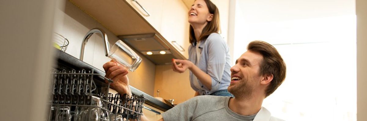 mosogatógépet használ egy férfi és egy nő nevetve