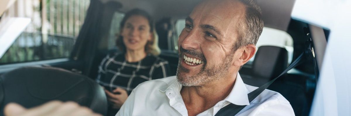 mosolygó taxisofőr a visszapillantó tükörben néz az utasra, aki hátul ül
