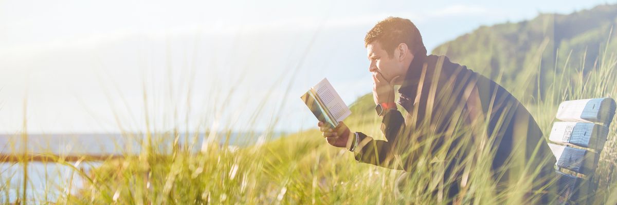Olvasó férfi a tengerparton, könyvvel a kezében