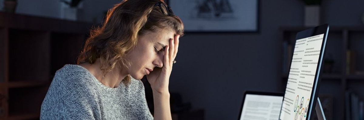stresszes nő fogja a fejét munka közben a számítógép előtt