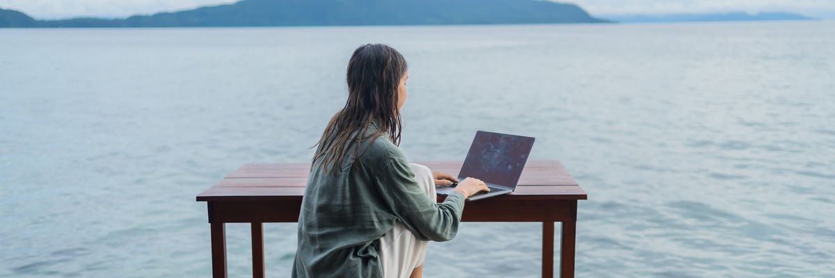 tóparton ülő nő laptopozik digitális nomád