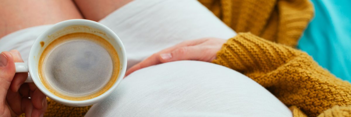 várandós kismama egy csésze kávéval a kezében