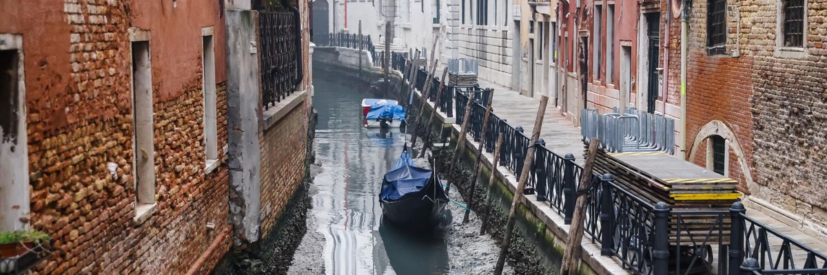 Velencei utcakép kevés vízzel és álló csónakokkal